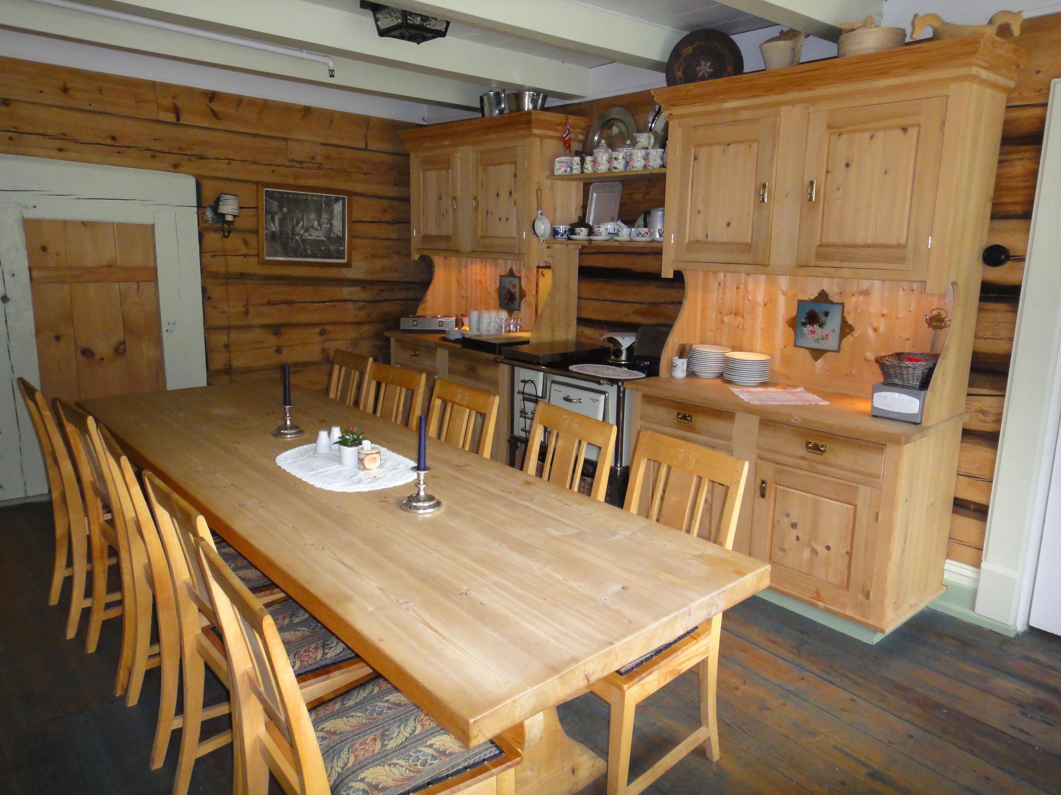 Homely dining area with log walls, long wooden table and traditional interior at Jaunsen Guesthouse in Hardanger, Norway.