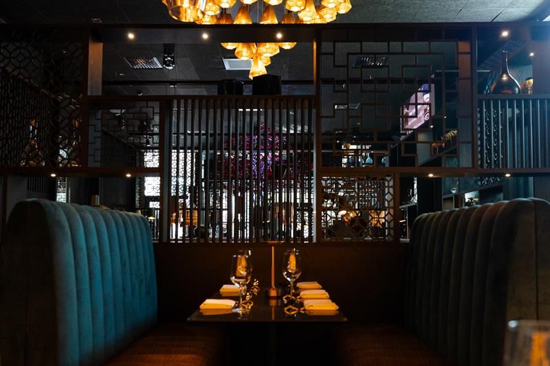 Green seating section and table set for dining, underneath a chandelier