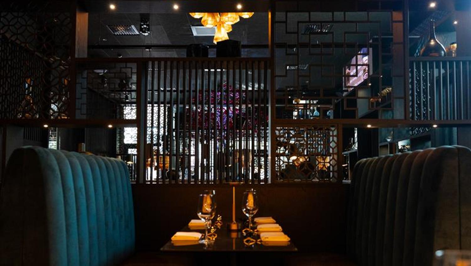 Green seating section and table set for dining, underneath a chandelier
