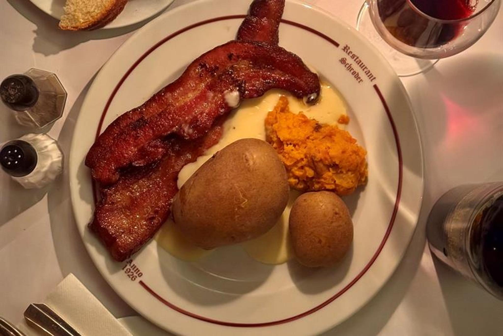 Tallerken med sprøstekt flesk, poteter og rotmos servert i varmt kveldslys.