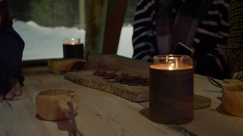 food on a tray with a candle light and  a wooden cup 