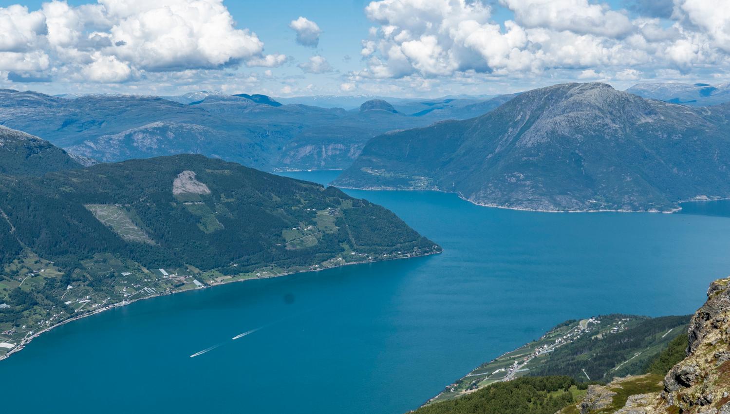 Panoramautsikt over Hardangerfjorden sett frå Dronningstien under ein klar, blå himmel.