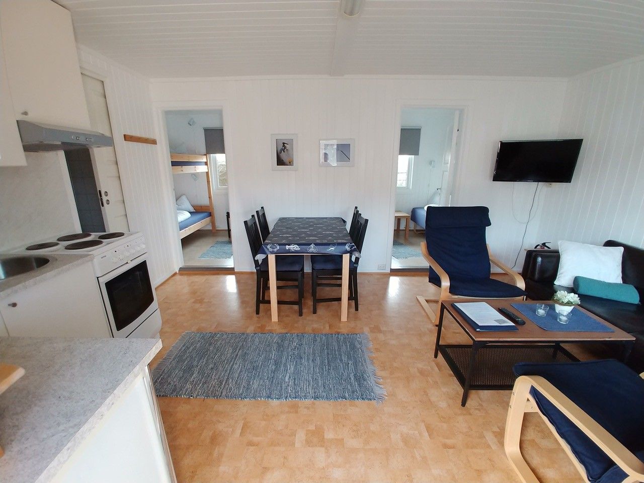 Living room with sofa, chairs, table, kitchen table and kitchen chairs, kitchen nook and view to the bedrooms