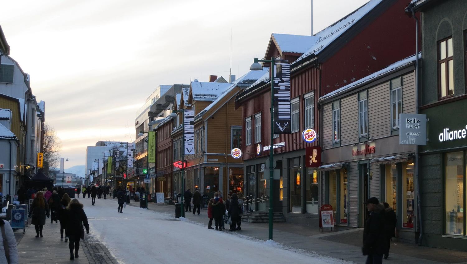 Snow-covered town street with people and shops.