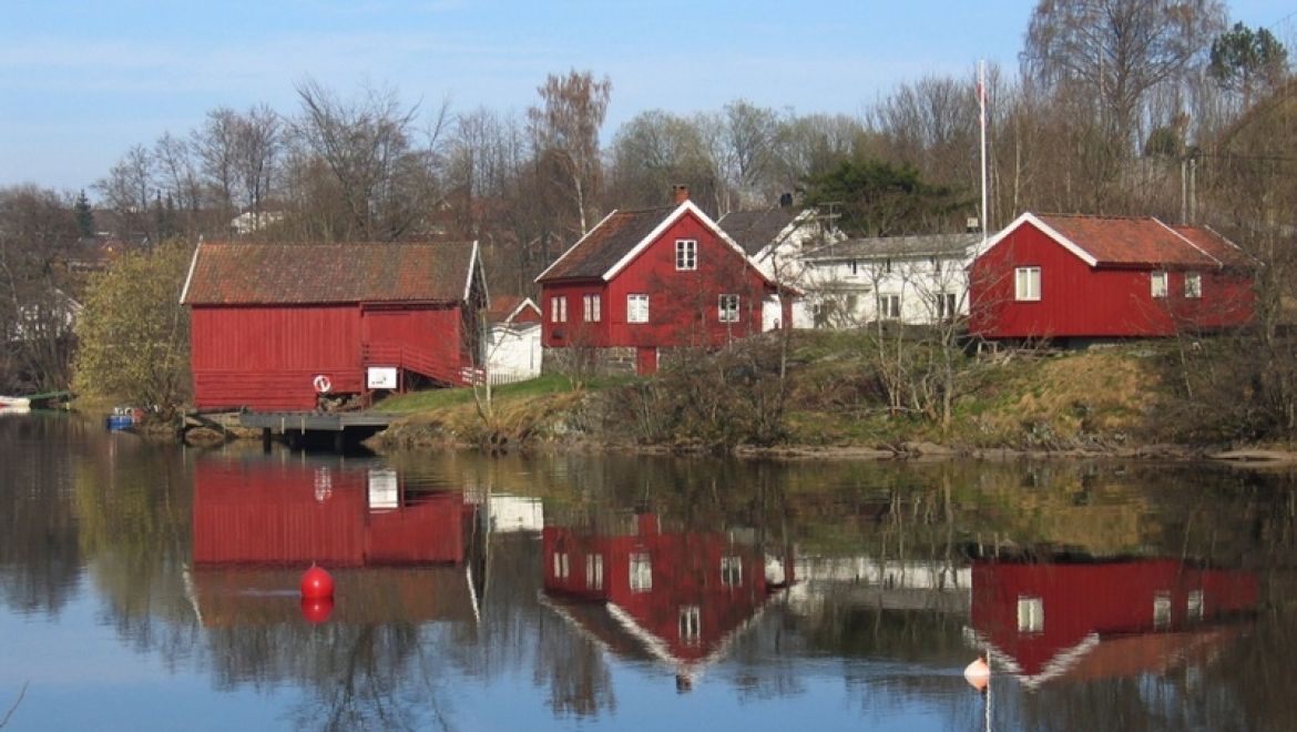 Bomsholmen Fløtingsmuseum med sine tre røde bygninger rett ved Nidelva i Arendal