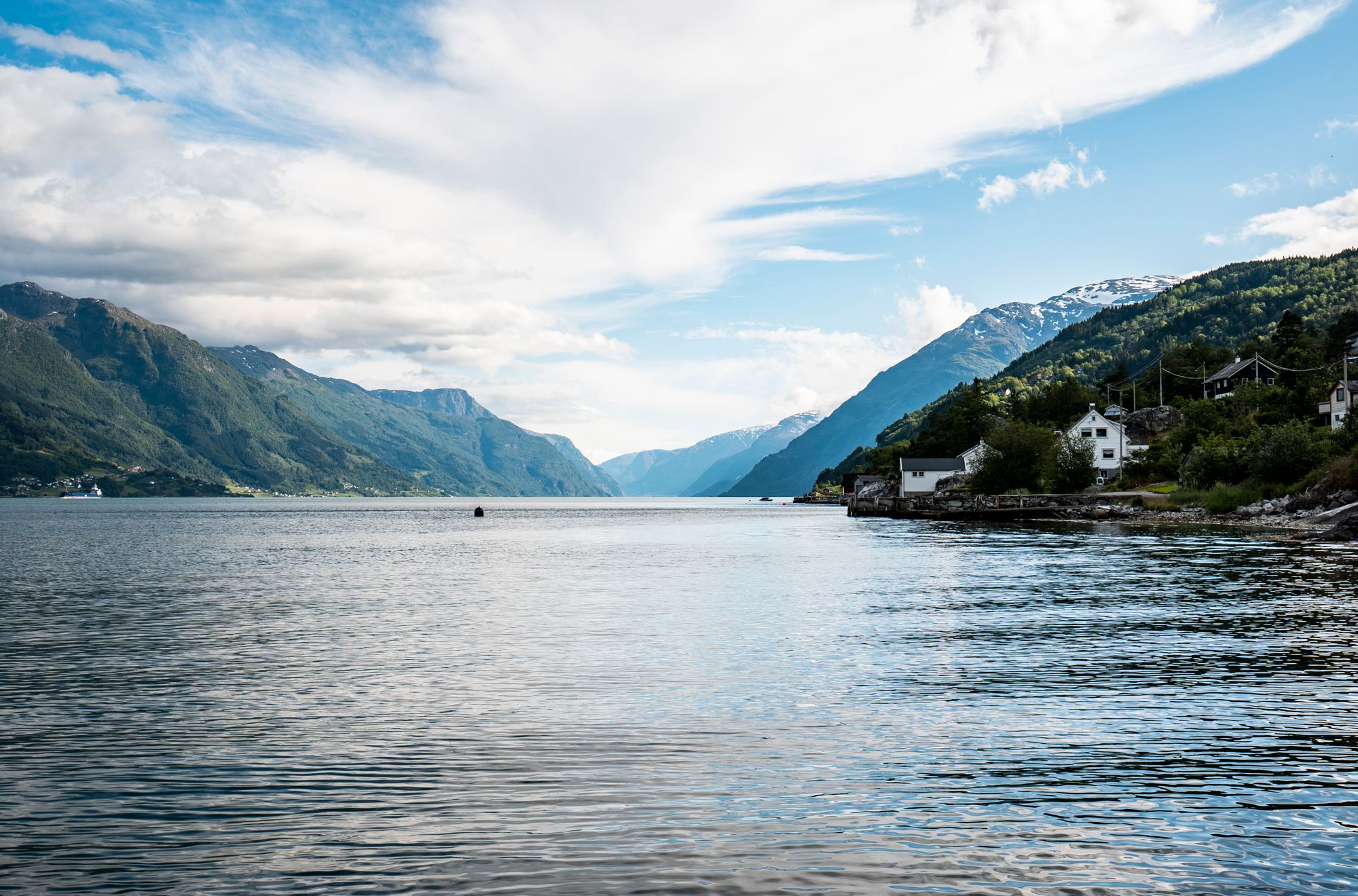 Sjarmerande fjordlandskap med idylliske hus langs Hardangerfjorden.