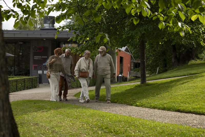 Visitors exploring a heritage site with historic buildings and green lawns.
