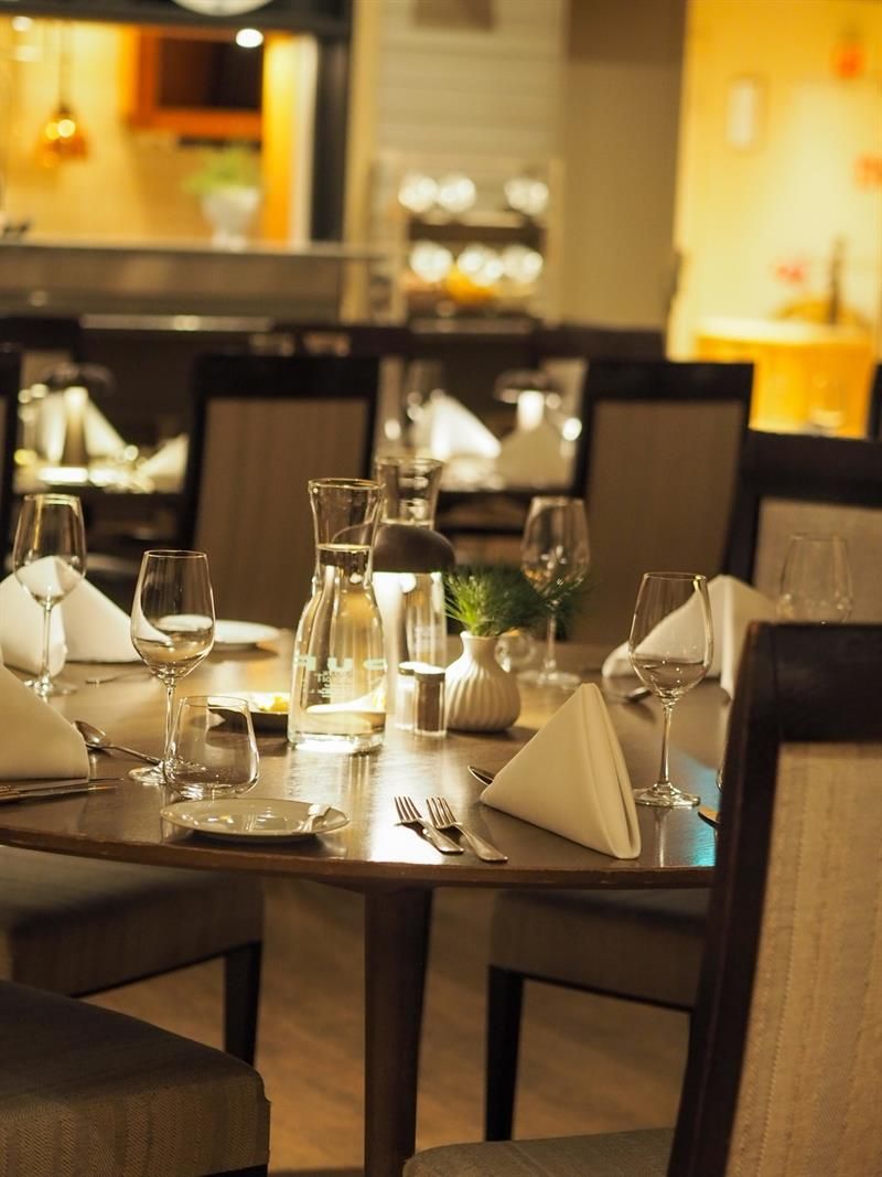 Stemningsfull restaurant med dekkede bord, dempet belysning og en varm atmosfære.
