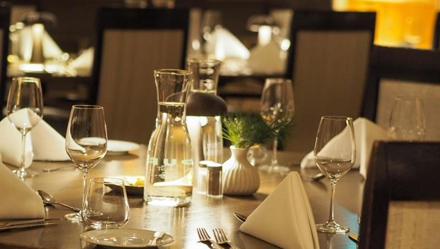 Stemningsfull restaurant med dekkede bord, dempet belysning og en varm atmosfære.