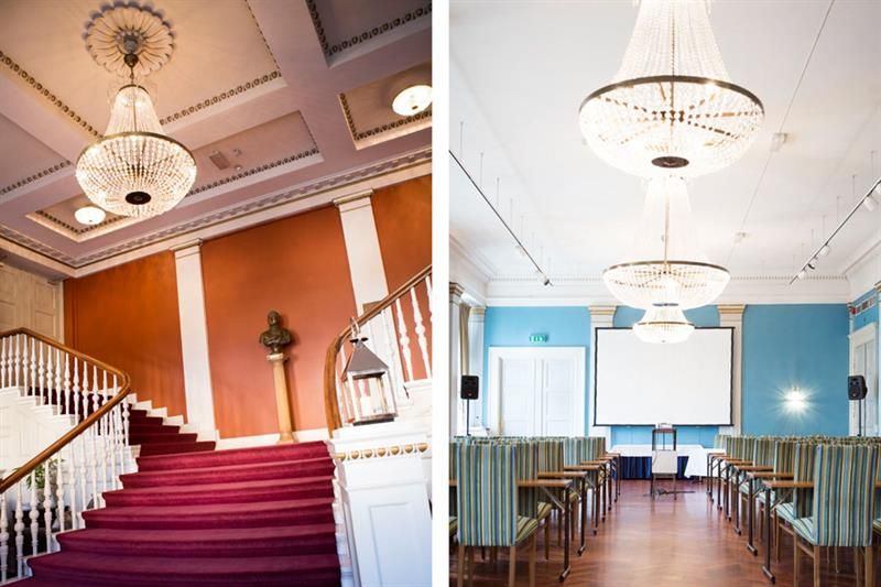 Photo of a staircase with red carpet and chandelier hanging from the ceiling, and a picture of a conference room with chairs and tables, and two chand