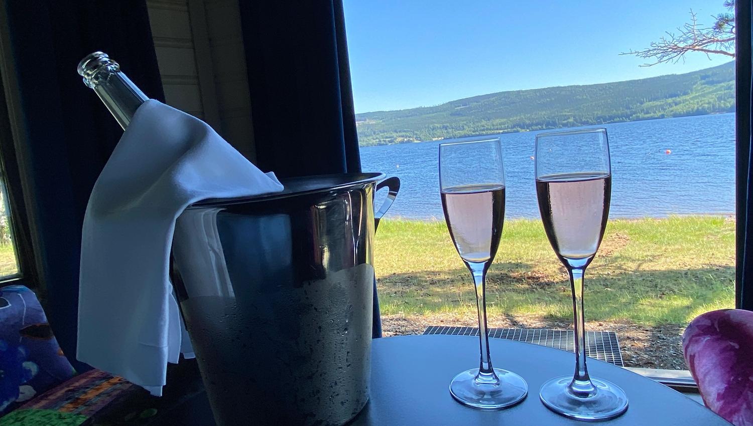 2 glasses with pink drinks on a table with view to a lake