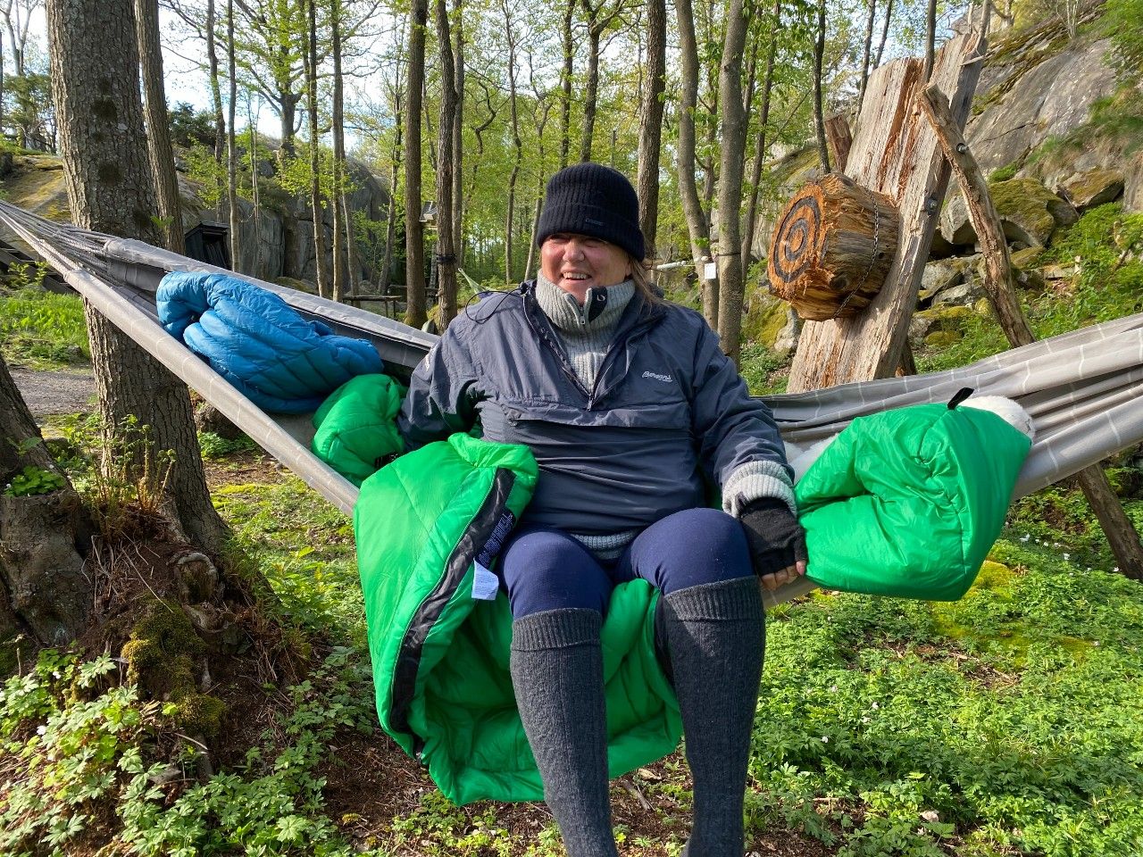 A happy lady has slept in a hammock between the trees. She is well dressed