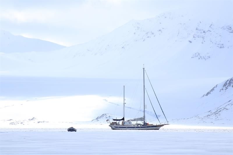 Seilbåt ligger i fjorden med fjell i bakgrunnen