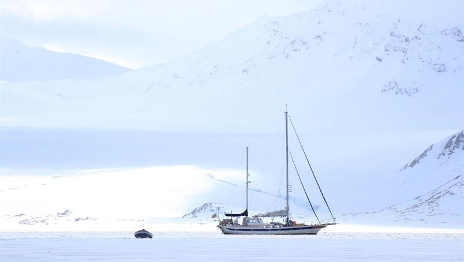 Seilbåt ligger i fjorden med fjell i bakgrunnen