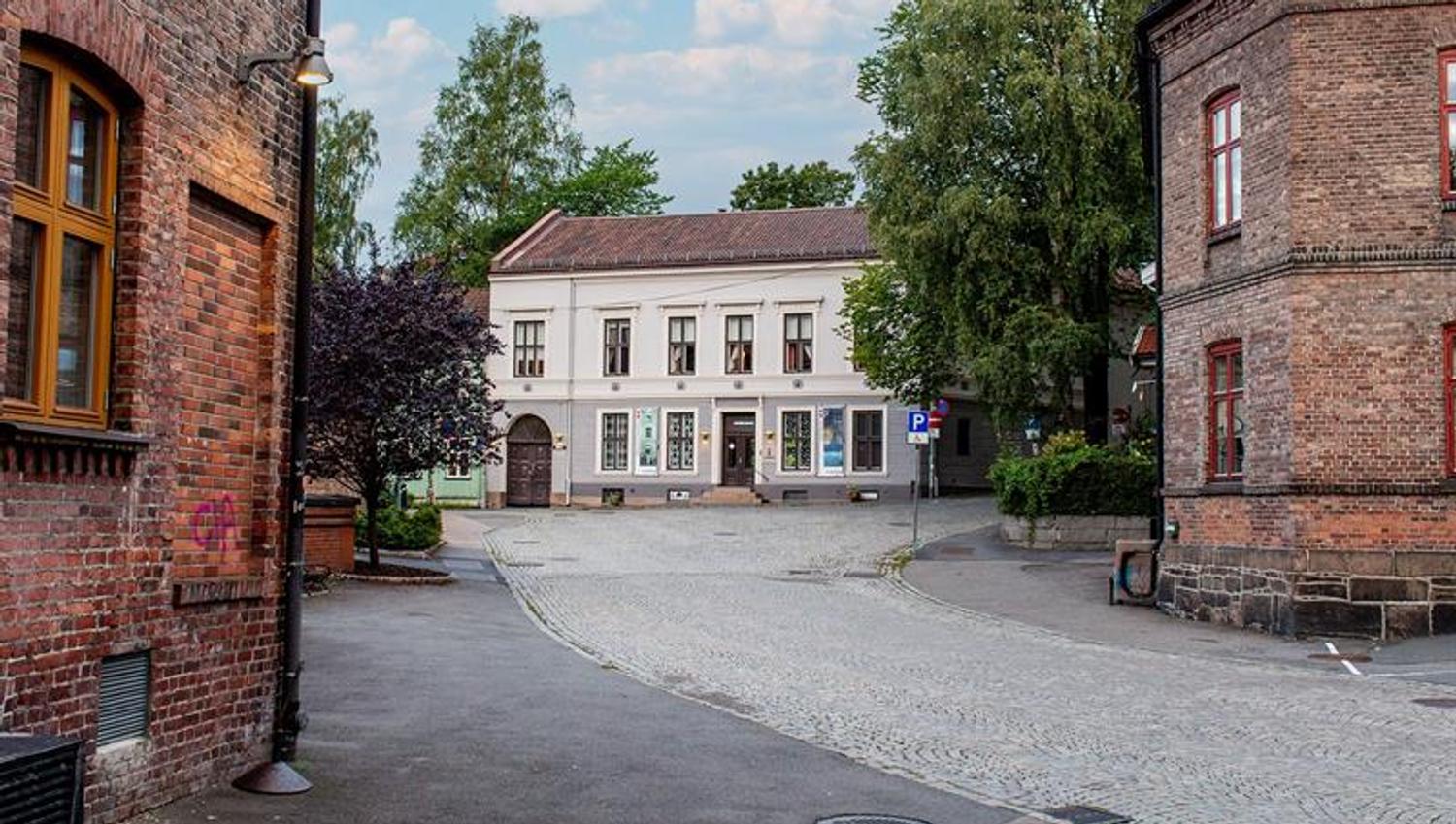 Exterior view of the Workers Museum in a quiet cobbled street surrounded by historic brick buildings and trees.