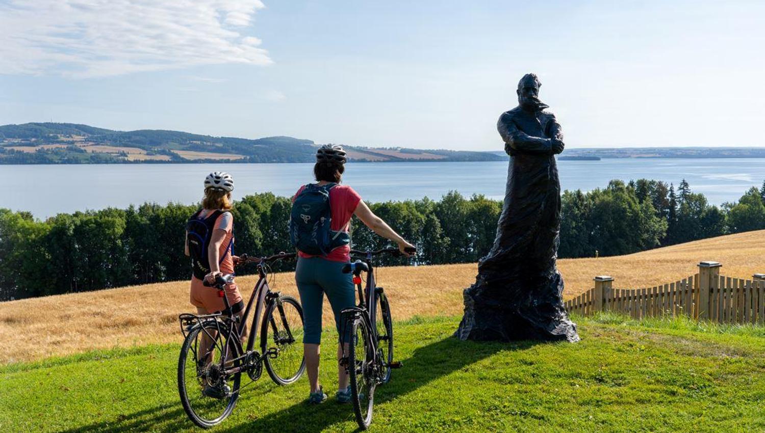 Peder Balke-senteret på Kapp i Østre Toten. Mjøstråkk-syklister nyter Mjøsutsikten ved Peder Balke statue.