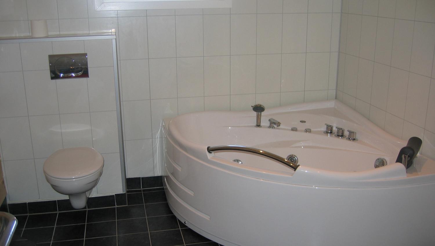 Bright and modern bathroom with a spacious corner bathtub.
