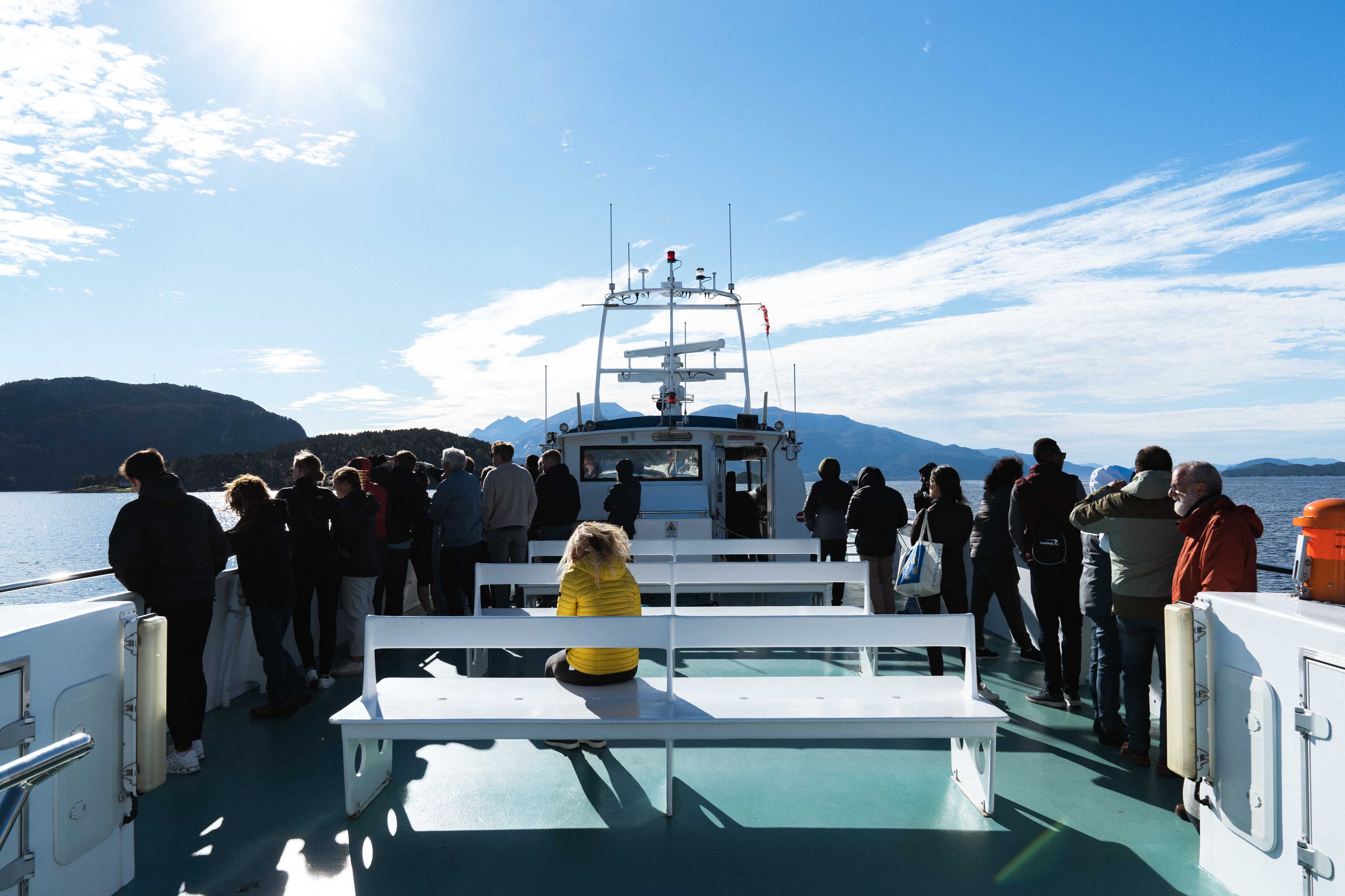 Passengers enjoying the sun and views from the deck of Hardangerfjordekspressen in Hardanger.