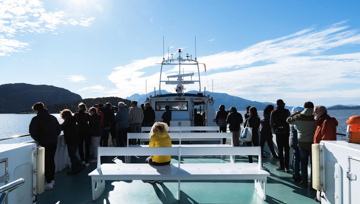 Passengers enjoying the sun and views from the deck of Hardangerfjordekspressen in Hardanger.