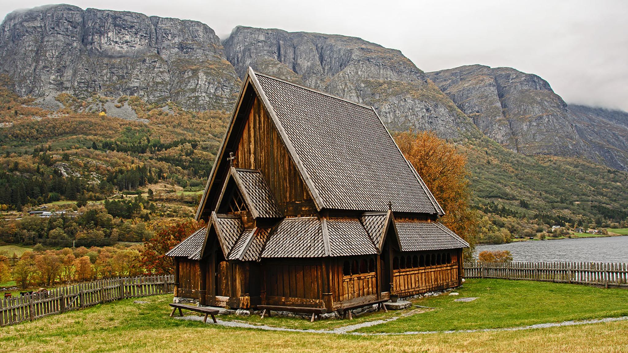 Øye Stavkirke med høstfarger på trærne i bakgrunnen.