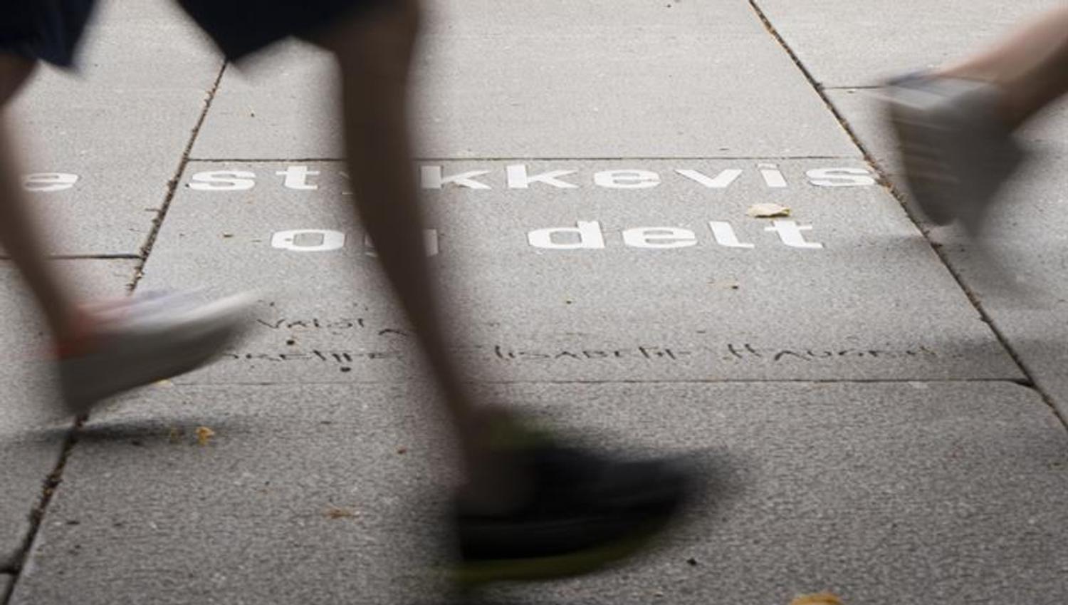 Feet walking past an Ibsen quote on the ground.
