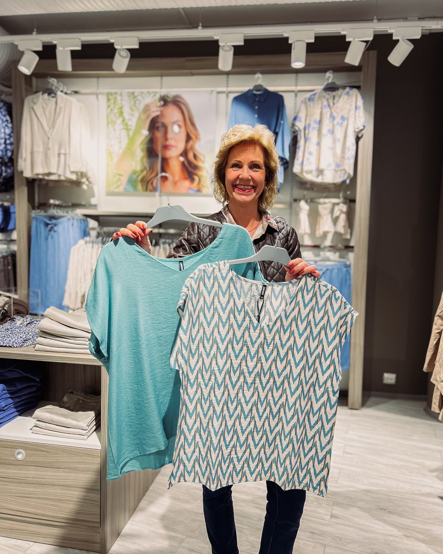 Smilende ansatt hos klesbutikken Zavanna, viser frem to bluser