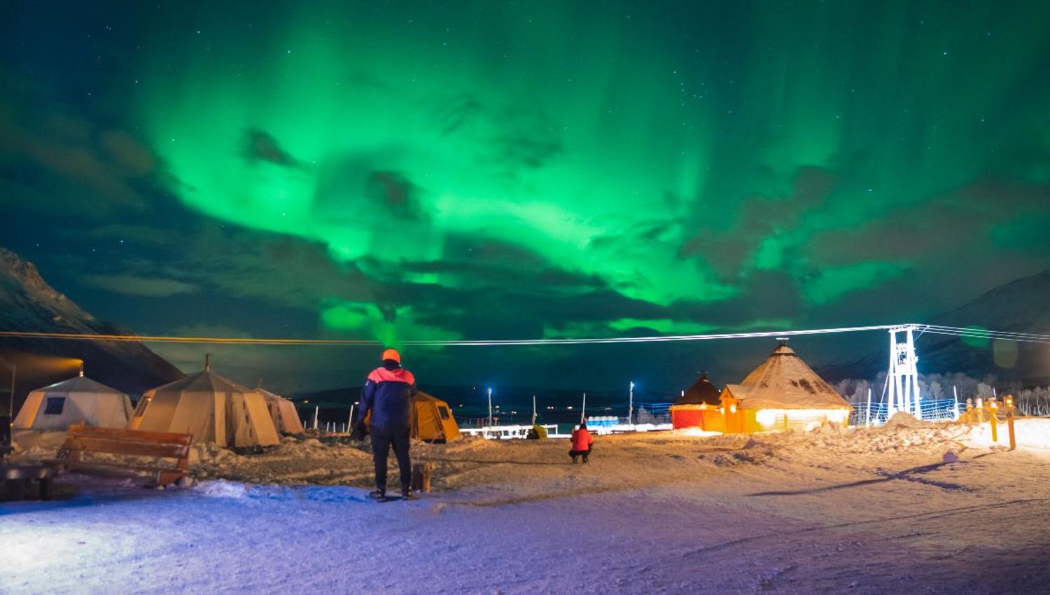 ght Northern Lights above Tromsø Lapland’s reindeer camp and lavvus in a snowy winter landscape.