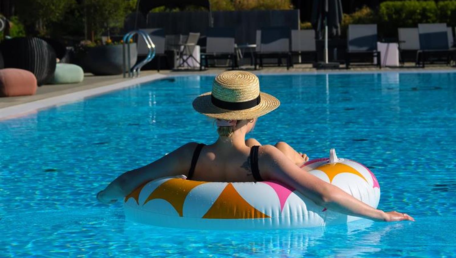 Outdoor pool The Well - lady with hat on a inflated madrass