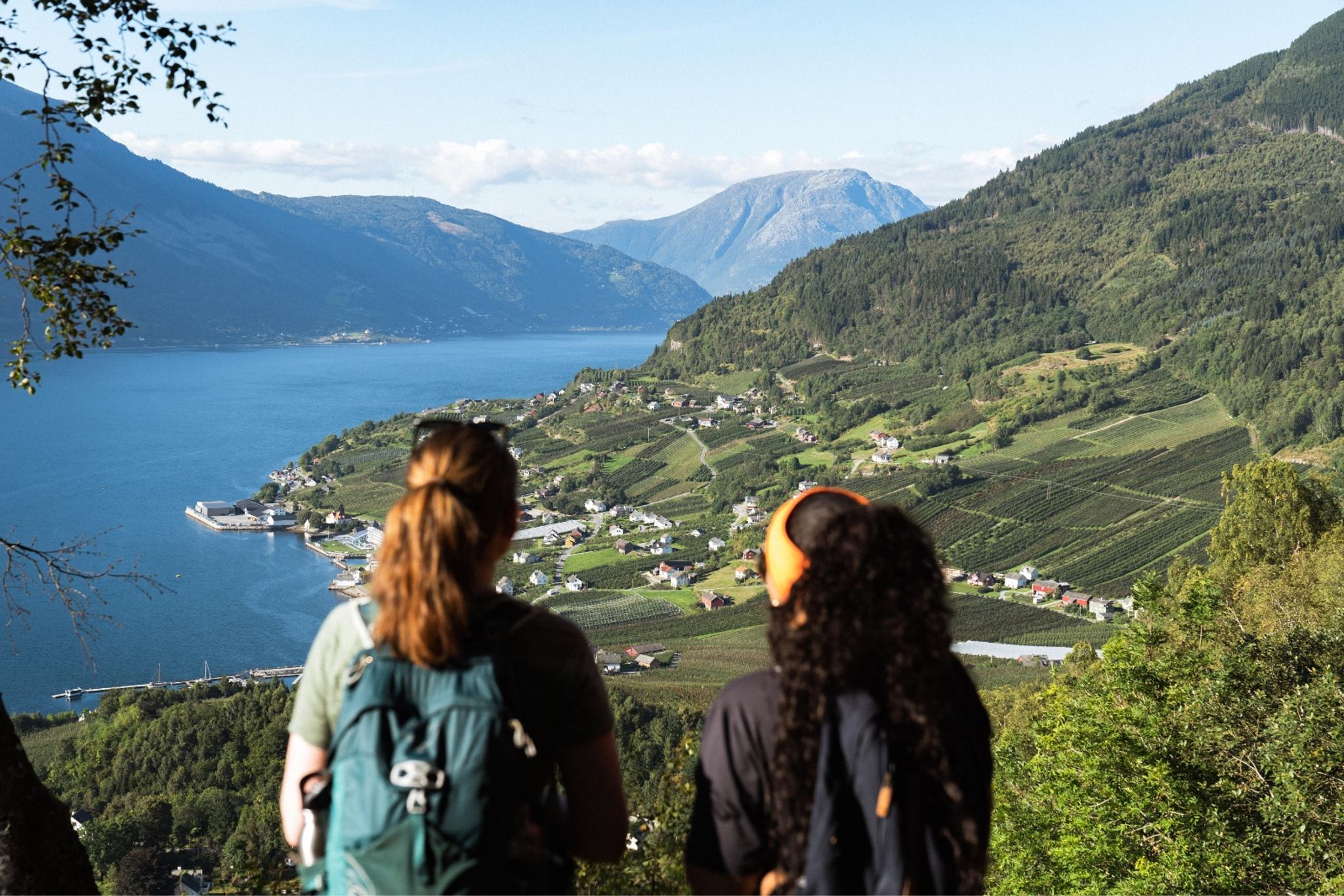 Two people looking at a view towards the Hardangerfjord and a village
