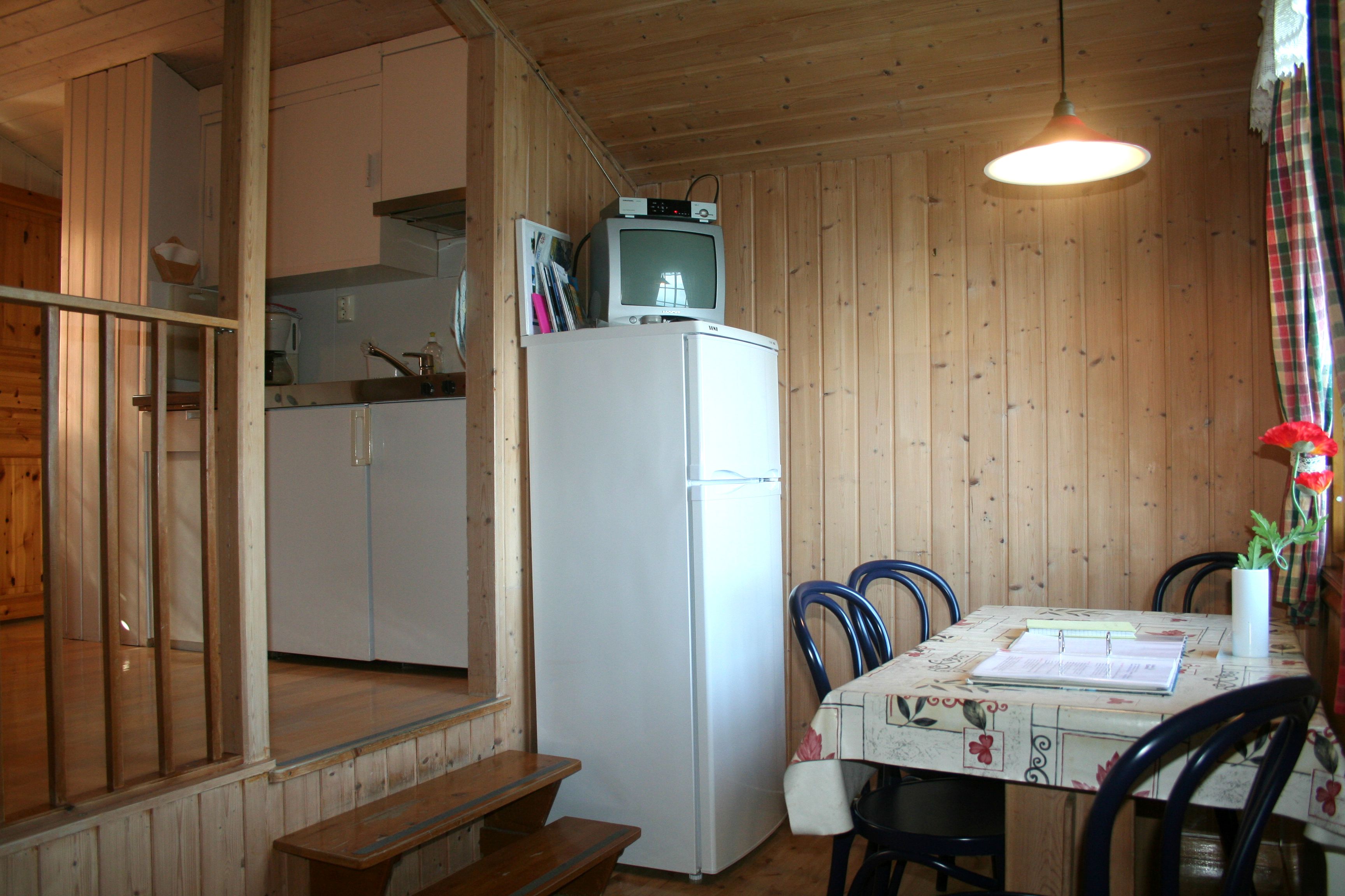 Traditional cabin kitchen with dining table and TV in an older cabin at Oddland Camping.