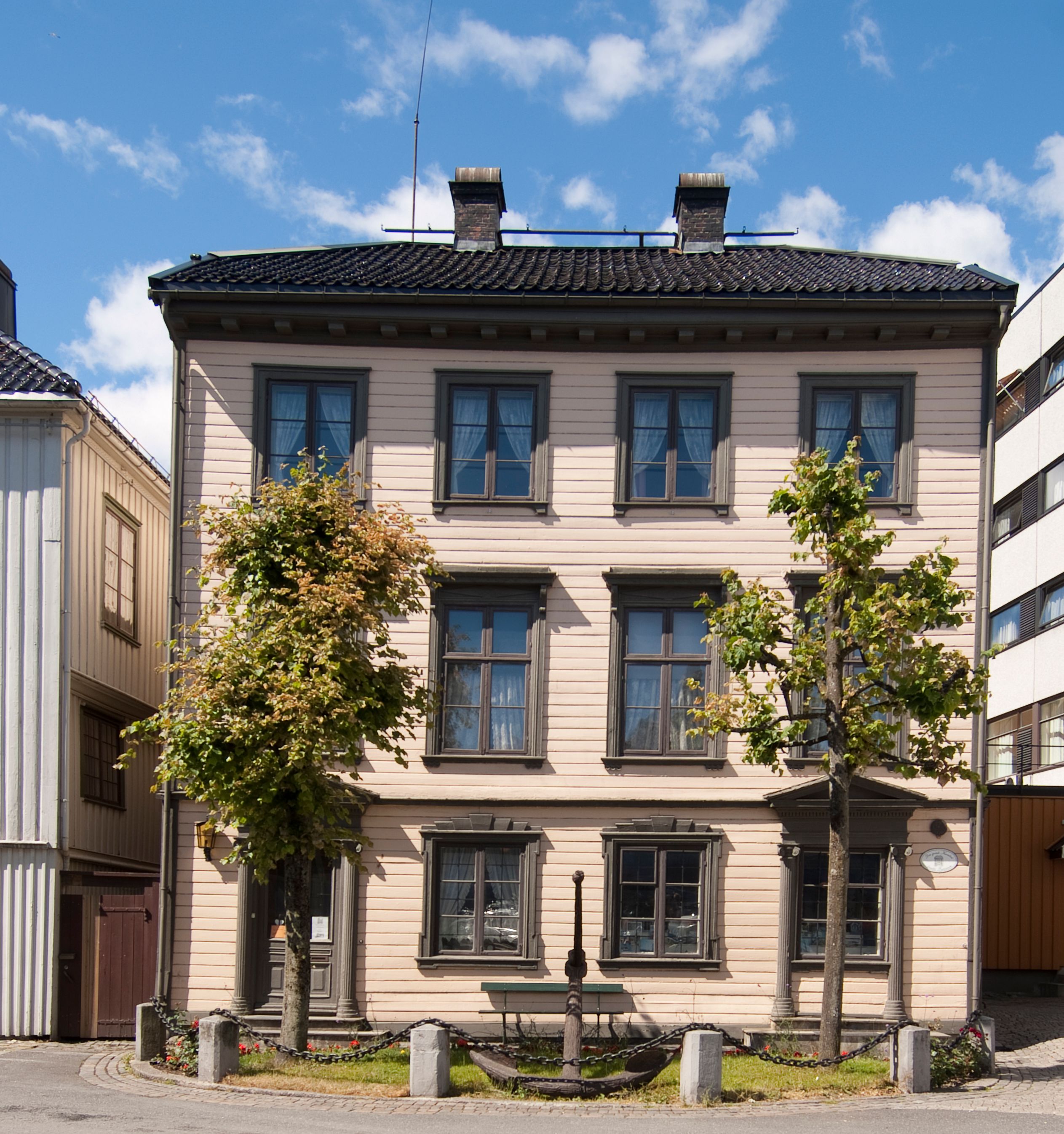 Frontfasade av Kløckers Hus, Arendal Bymuseum fra 1826. trehus i tre etasjer, beige liggende panel med militærgrønne vinduskarmer.
