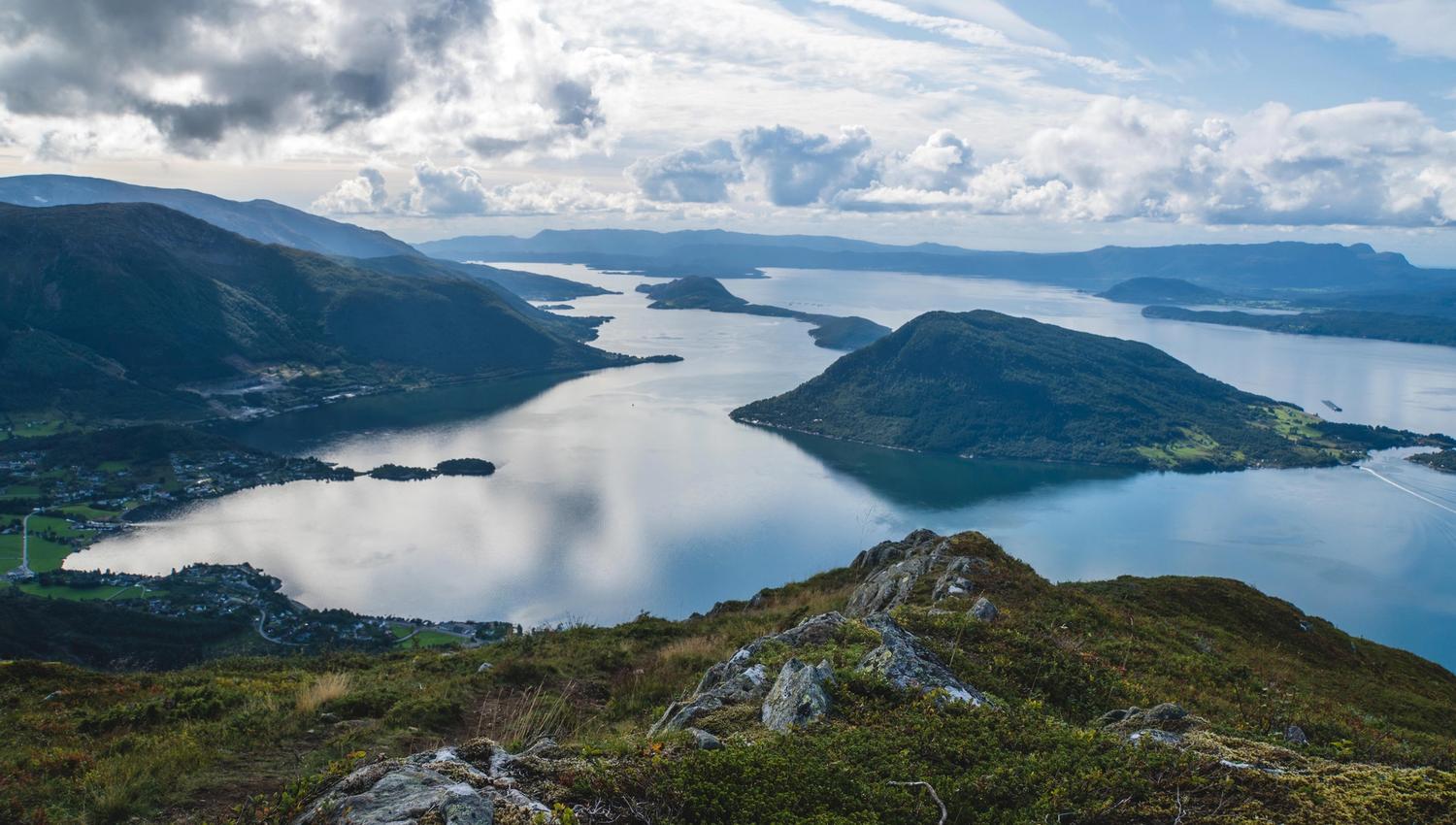Storslått utsikt frå Malmangernuten over Hardangerfjorden med fjell, øyar og dramatisk skyspel.