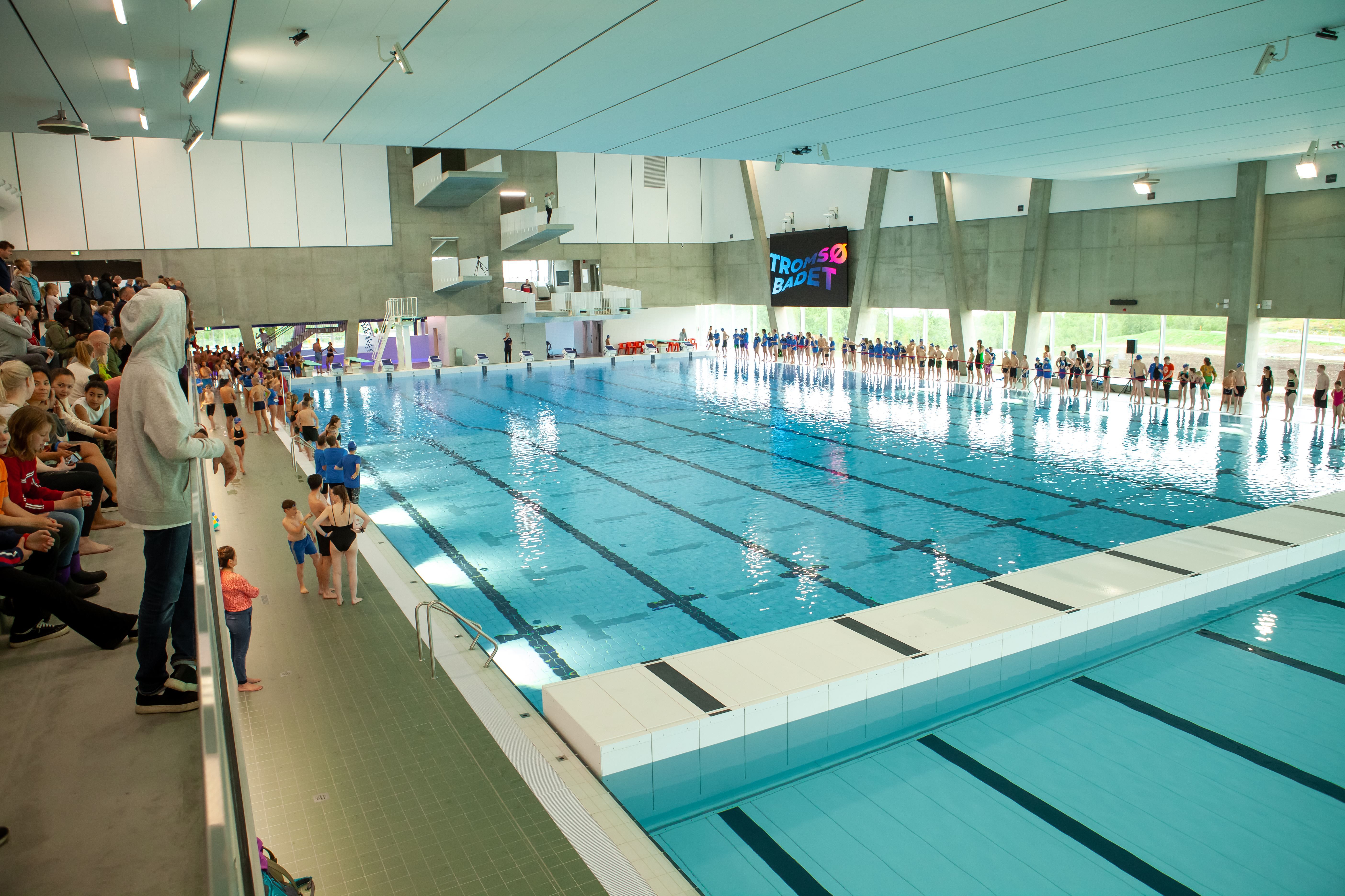 Indoor swimming pool with spectators and the sign TROMSØ BADET on the wall