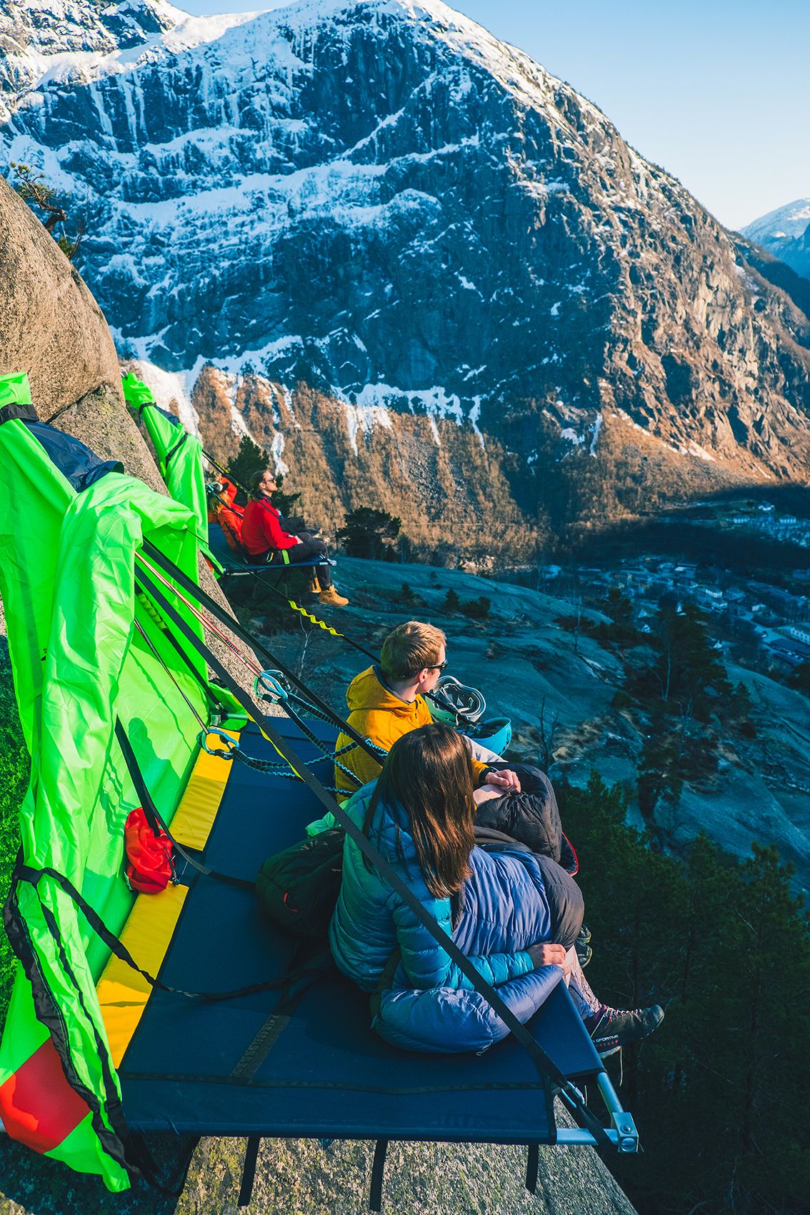 Fleire turgåarar slappar av på portaledges ved fjellsida, med utsikt over fjordlandskapet i Hardanger. Ei unik naturoppleving.