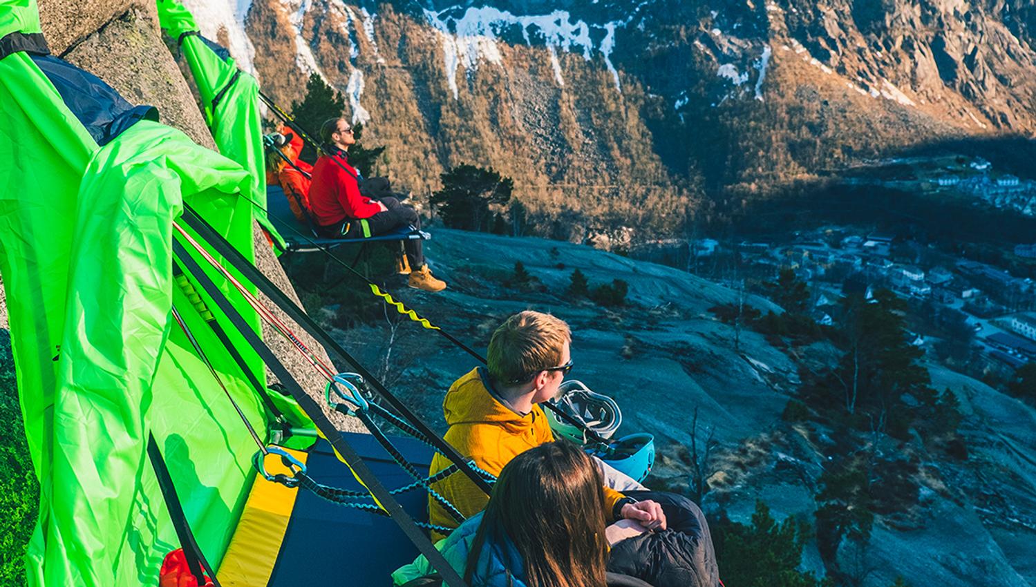 Fleire turgåarar slappar av på portaledges ved fjellsida, med utsikt over fjordlandskapet i Hardanger. Ei unik naturoppleving.