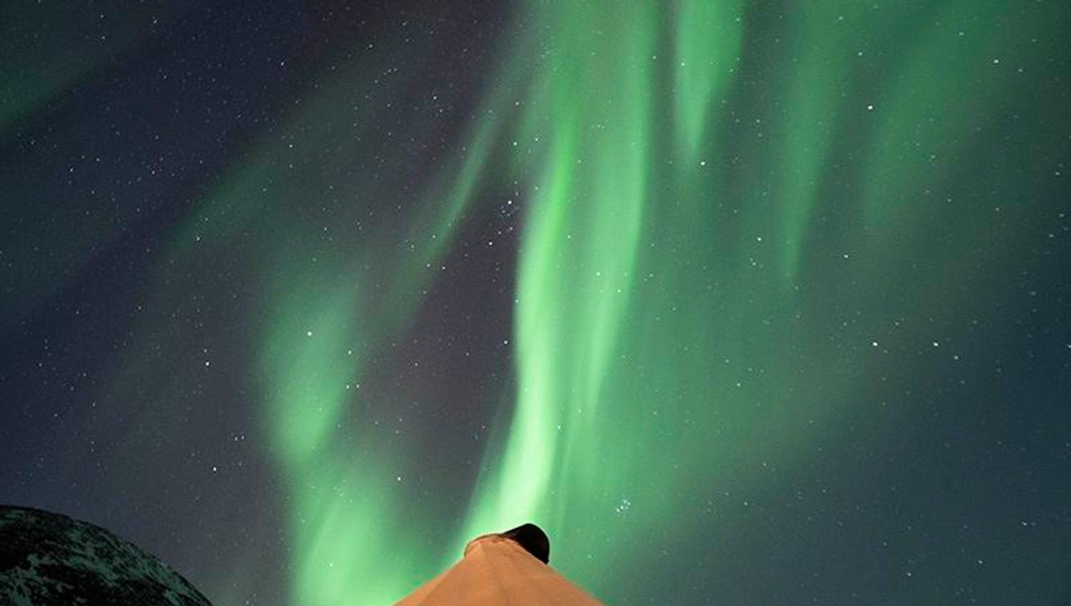 The Northern Lights show themselves above a lavvo