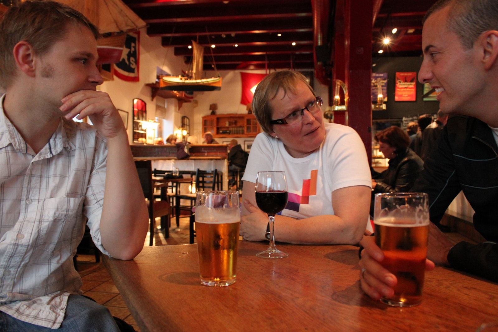 Three people at a table with beer and wine in a nautically themed bar.