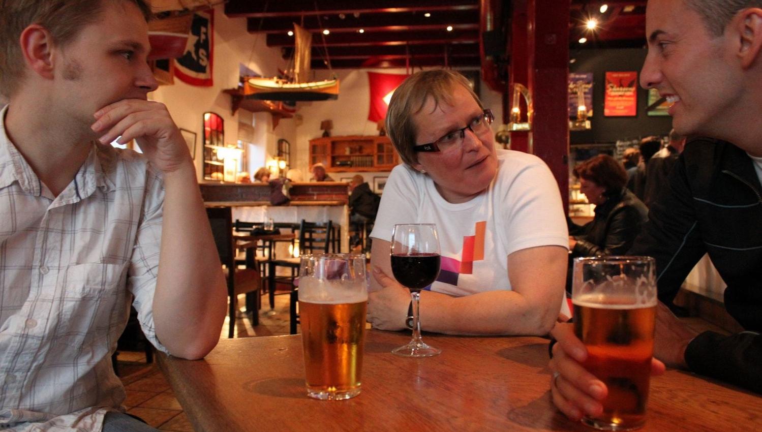 Three people at a table with beer and wine in a nautically themed bar.