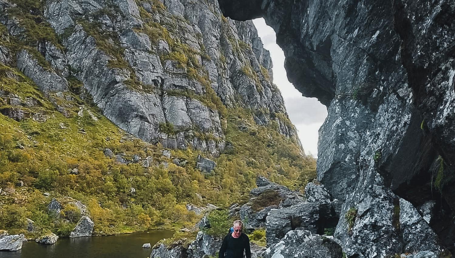 Hiker walking through a narrow mountain valley in Hardanger, Norway, with water and dramatic rock formations