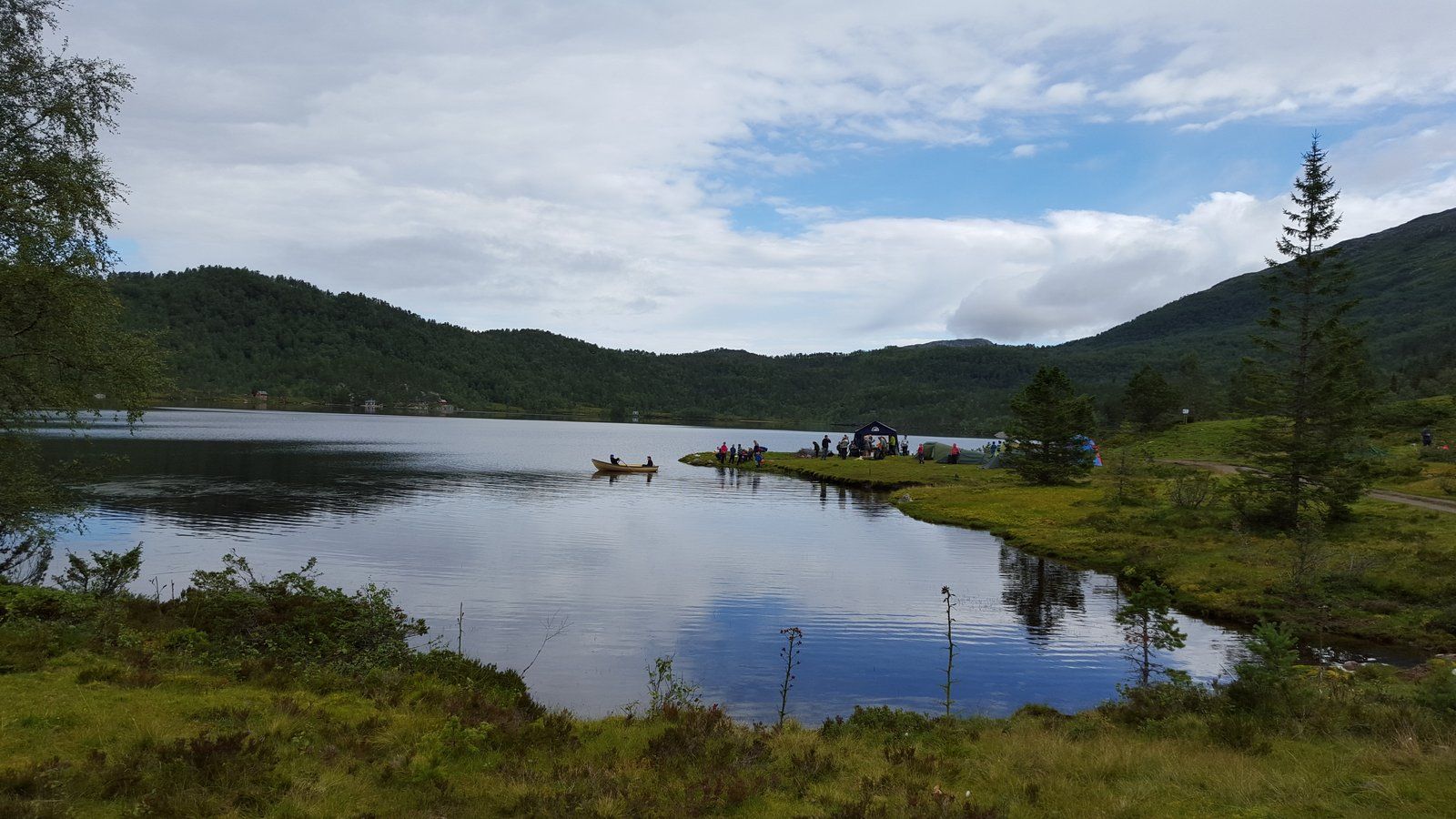 Peaceful day by the lake with boats and tents at Folgefonn Cabins and Farm Camping in Hardanger.