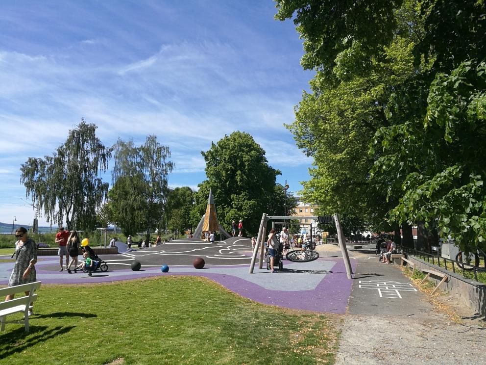 A green park with walking paths, playground equipment, and open spaces, an area for play, relaxation, and enjoying the surroundings.