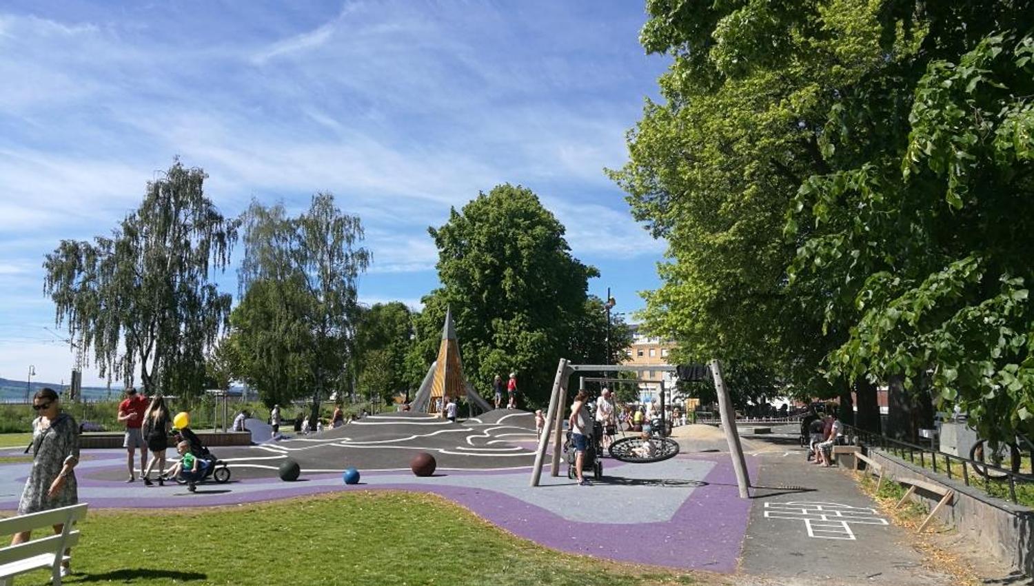 A green park with walking paths, playground equipment, and open spaces, an area for play, relaxation, and enjoying the surroundings.