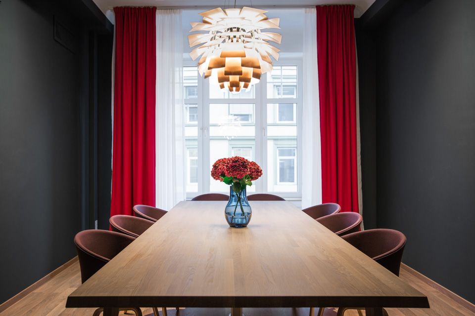 Møterom med åtte sitteplasser ved langbord, Røde gardiner, røde blomster. Hotell Bondeheimen, Oslo. Foto