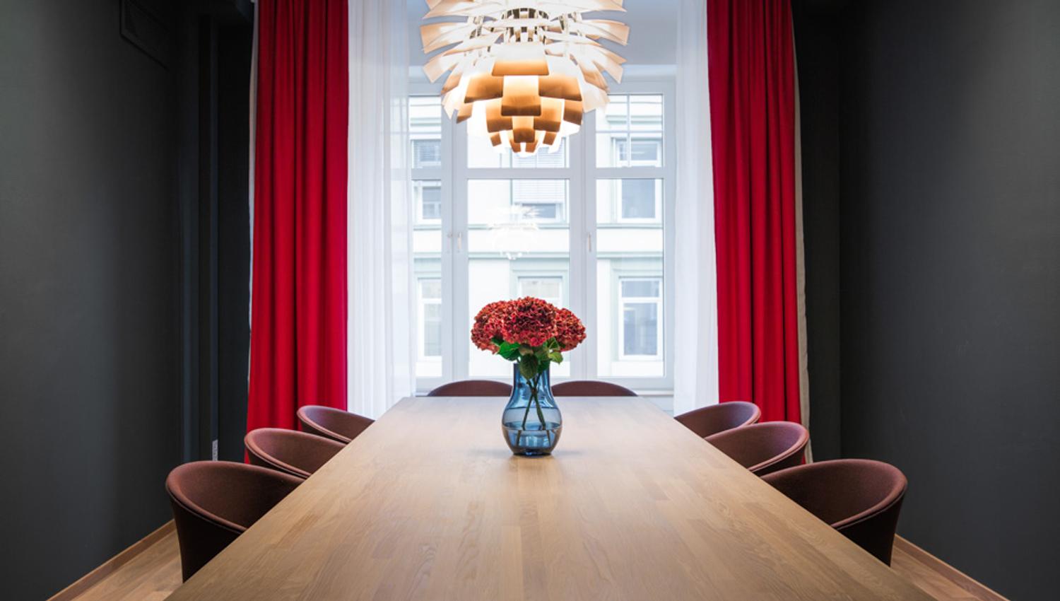Møterom med åtte sitteplasser ved langbord, Røde gardiner, røde blomster. Hotell Bondeheimen, Oslo. Foto