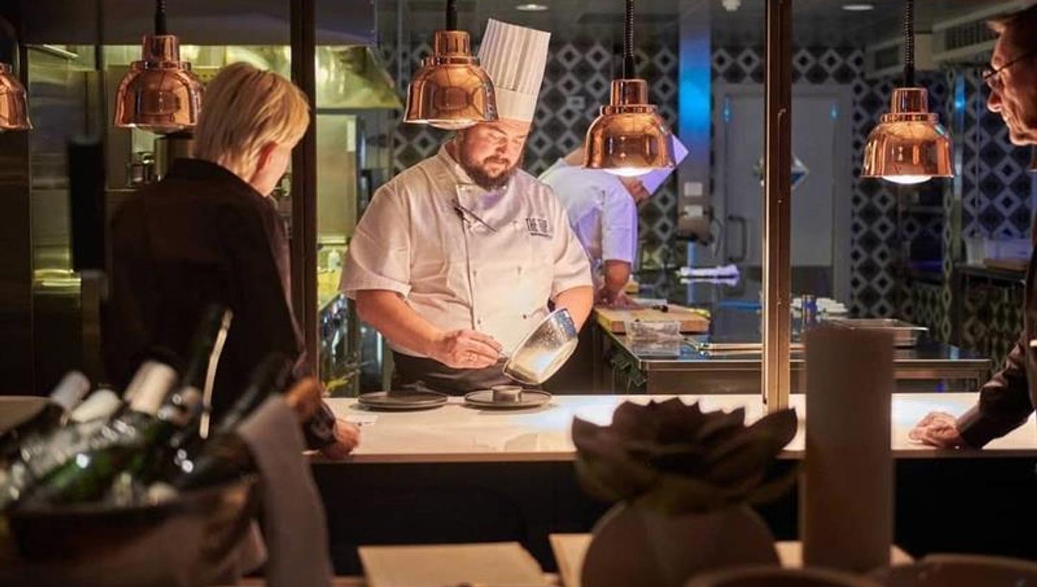chef preparing food in front of people in an open kitchen