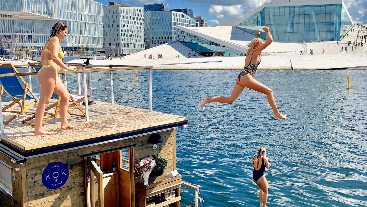People jumping into the water with the opera in the background.