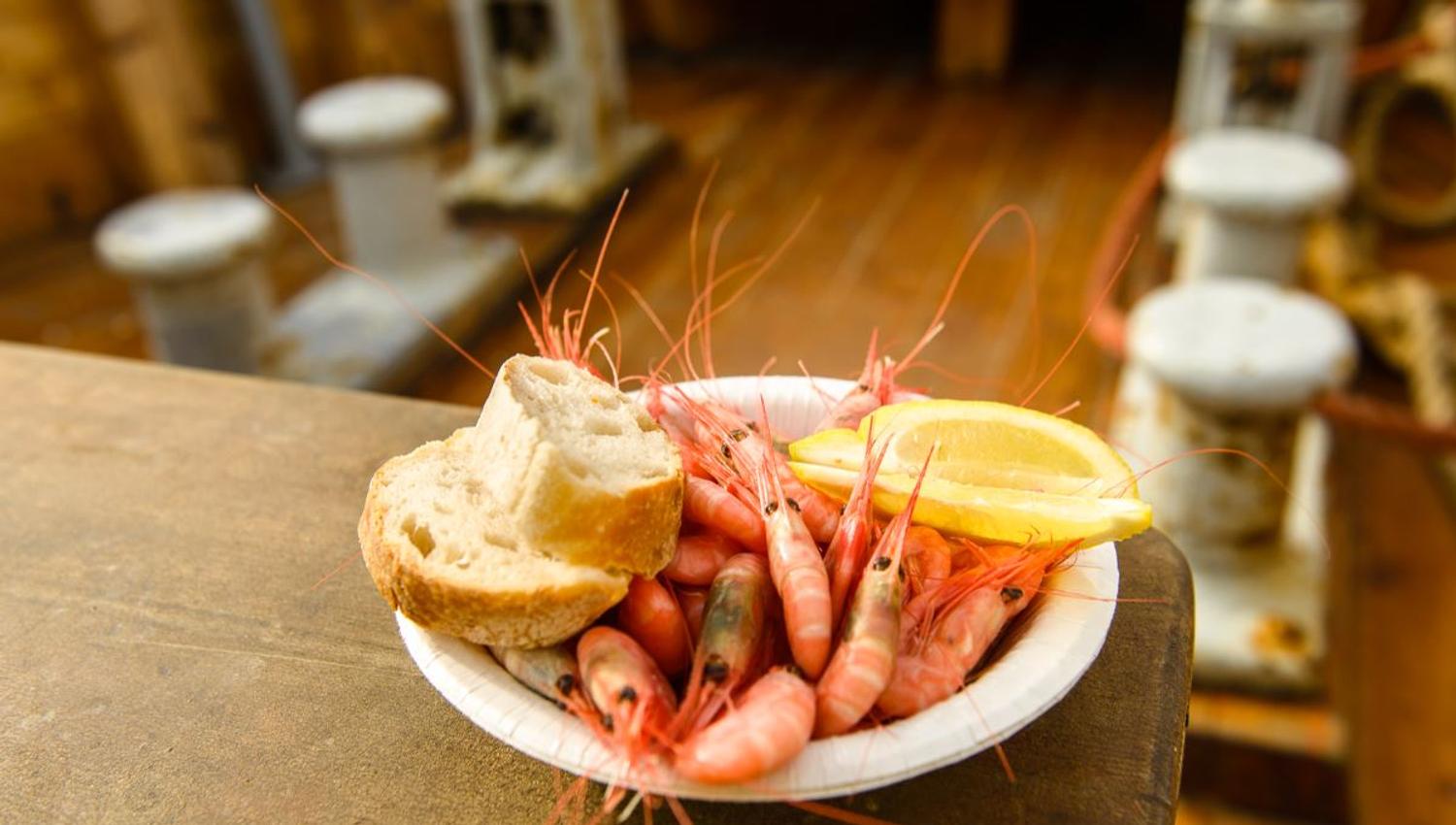 Shrimp in a bowl with bread and a slice of lemon