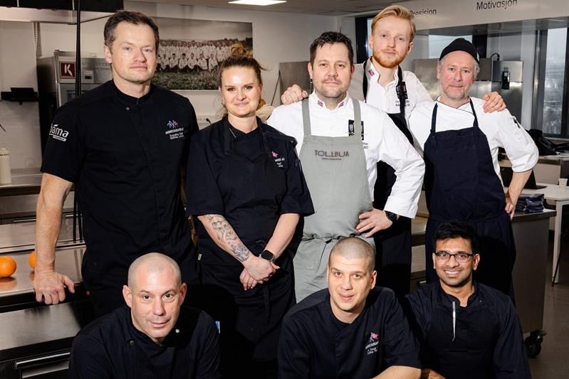 Chefs posing in a kitchen.