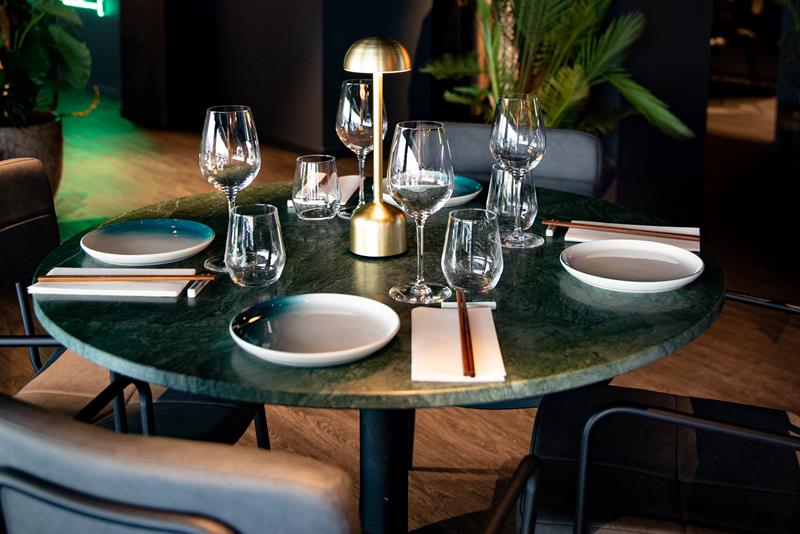 Round dining table with gold lamp, plates, glasses and crockery on