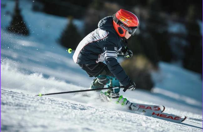 Gutt med rød hjelm står slalom